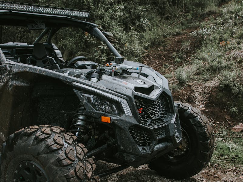 UTV equipped with RECON TRAIL off-road tires driving through a rugged forest trail.