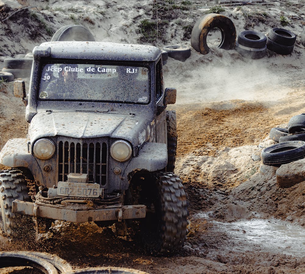 Off-road Jeep driving through muddy terrain equipped with rugged RECON TRAIL off-road tires.